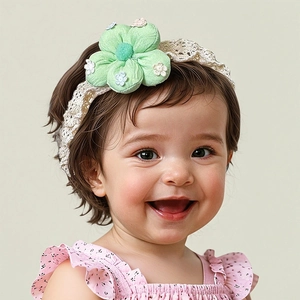 Détail d'un bandeau bébé avec fleur en tissu vert et dentelle au crochet beige