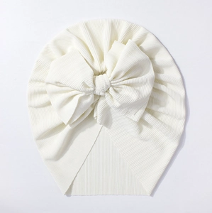 Détail de la texture en maille côtelée et du grand nœud sur ce bonnet blanc pour bébé