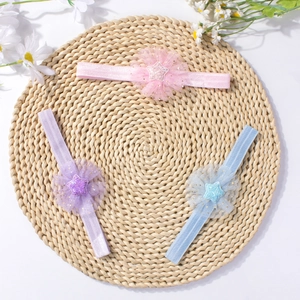 Three-piece set of mesh flower baby headbands with sparkly stars on a natural straw mat