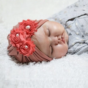 Détail du bandeau pour bébé rose rétro avec trois fleurs en tissu et des perles