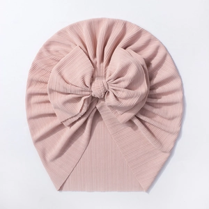 Détail d'un bonnet turban pour bébé avec grand nœud et coton côtelé rose doux