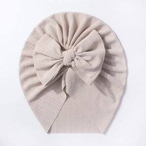 Détail du bonnet côtelé pour bébé avec un grand nœud de couleur crème champagne