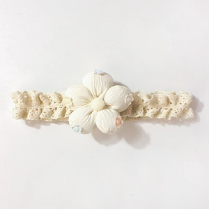 Gros plan du bandeau en dentelle beige pour bébé avec broderie florale en coton