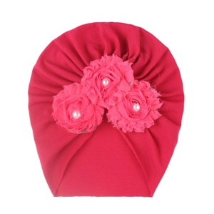Détail du bonnet turban rose pour bébé avec trois fleurs en tissu et perles