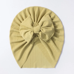 Détail du turban pour bébé en tricot côtelé jaune moutarde avec un grand nœud décoratif