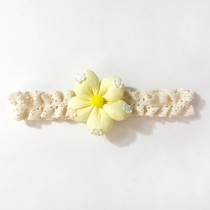 Détail du bandeau en dentelle pour bébé avec fleur en tissu jaune et broderie délicate