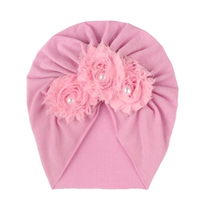 Bonnet turban rose pour bébé avec trois fleurs en tissu 3D et perles sur fond blanc