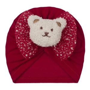 Détail du bonnet rouge pour bébé avec un grand nœud en tulle rose et un petit ours peluche