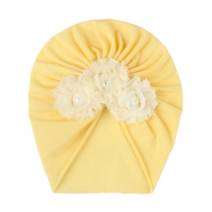 Détail du turban bébé jaune avec trois fleurs en tissu crème et perles centrales