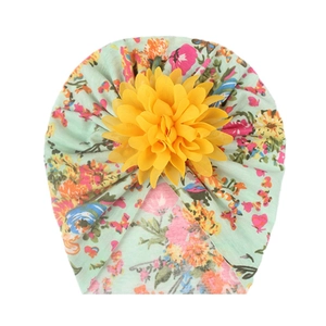 Detail of mint green baby turban hat with floral print and large yellow flower decoration