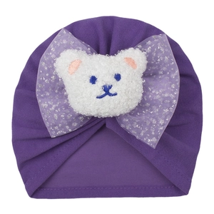 Détail du bonnet turban violet pour bébé avec nœud en maille pailletée et ours en peluche