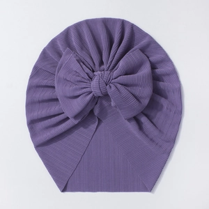 Détail d'un bonnet turban pour bébé en tricot côtelé violet avec un grand nœud décoratif