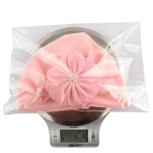 Pink velvet baby turban hat with decorative flower weighing 27.2g on a scale