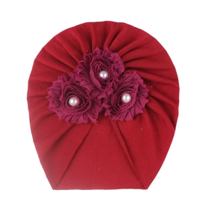 Détail du bonnet turban rouge pour bébé avec trois roses en tissu et perles