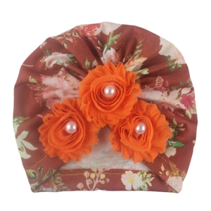 Detail of floral baby turban hat in brown with three orange fabric flowers and pearls