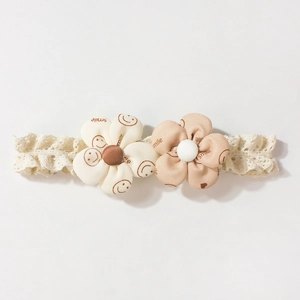 Detail of floral baby headband with lace texture and two hand-made fabric flowers