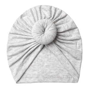 Detail of light grey knitted baby donut hat with soft texture and elastic fabric