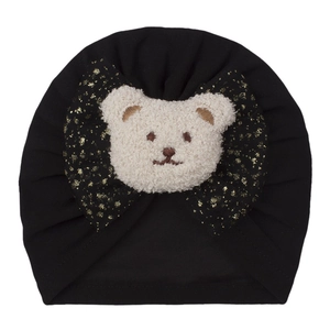 Détail du bonnet donut bébé avec nœud à paillettes noires et décor ours peluche