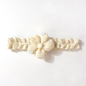 Détail du bandeau en dentelle pour bébé avec une fleur en tissu brodée crème