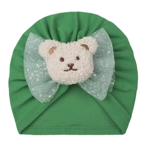 Détail du bonnet vert en coton pour bébé avec ours en peluche et nœuds en tulle à paillettes