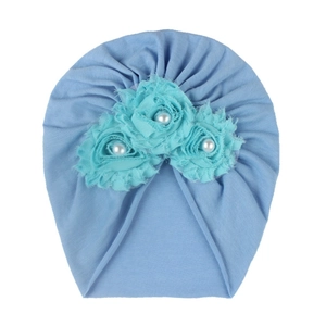 Détail du turban bébé bleu clair avec trois fleurs en tissu et perles nacrées