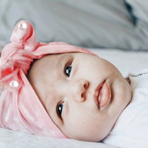 Detail of pink velvet baby headband with pearl accents on a soft knotted bunny ear hat