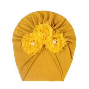 Détail du turban pour bébé orné de trois fleurs en tissu et perles nacrées