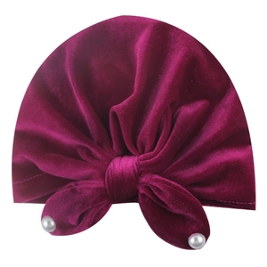 Detailed view of burgundy velvet baby turban hat featuring a large bow with white pearls