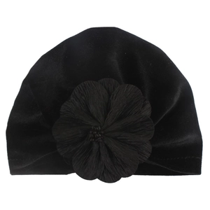 Close-up of a soft black velvet baby turban hat with a large layered flower detail