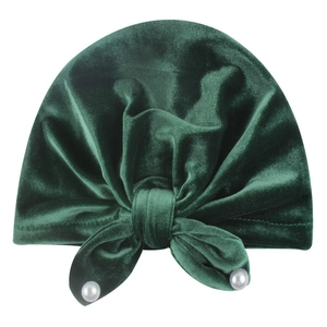Detail of dark green velvet baby hat with a large bow and elegant white faux pearls