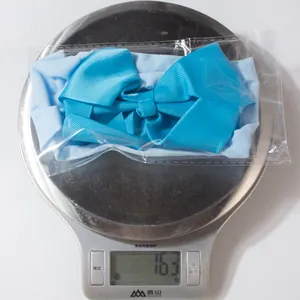 Sky blue ribbed bow headband for babies shown on a scale weighing 16.3 grams