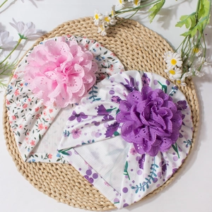 Détail de bonnets fleuris pour bébés avec de grandes pétales sur tissu côtelé