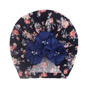 Détail de turban pour bébé avec imprimé floral et trois fleurs en mousseline 3D