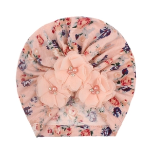 Détail d'un bonnet turban pour bébé rose à fleurs en mousseline et perles nacrées