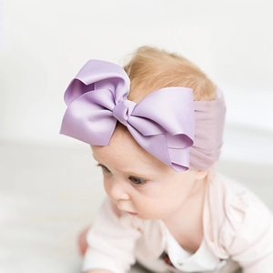 Close-up of baby girl wearing purple bow headband made of ribbed textured fabric