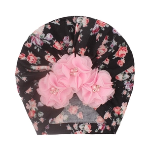 Bonnet turban bébé avec fleurs en mousseline rose et perles sur tissu floral noir
