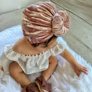 Detailed texture of pink velvet baby turban hat with donut knot on soft faux fur