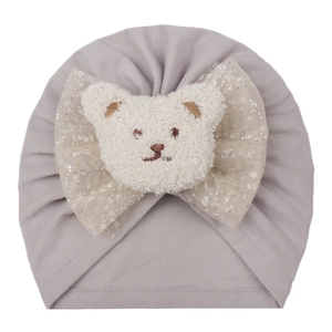 Light gray baby turban hat featuring a large silver mesh bow and plush bear detail