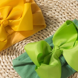 Close-up of bright yellow and green baby headbands with large ribbed bow accents