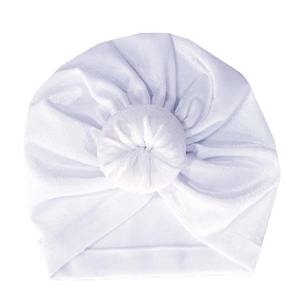 Detail of white velvet baby turban hat featuring a soft doughnut knot and silky texture