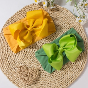 Baby headband set with large cute bows in yellow and green colors on straw background