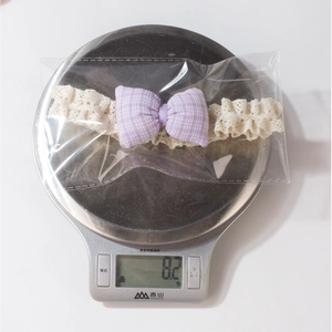 Spitzen-Baby-Stirnband mit lila Karoschleife wiegt 8,2 g auf einer Waage verpackt