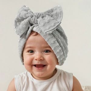 Detailed view of light gray baby beanie with textured polka dots and a large bow