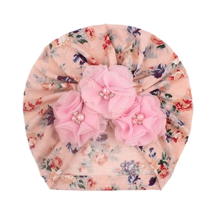 Détail du bonnet turban pour bébé avec fleurs en tissu rose, perles et strass brillants