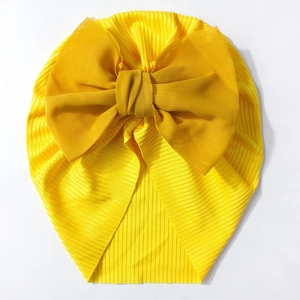 Détail d'un bonnet turban bébé jaune vif avec un grand nœud décoratif en mousseline