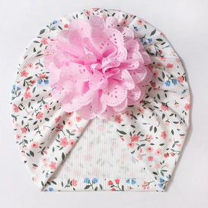 Détail du bonnet élastique pour bébé avec imprimé floral et grande fleur en dentelle