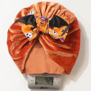 Détail d'un turban bébé en velours orange avec nœud d'ailes de chauve-souris Halloween