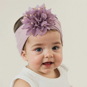 Détail du bandeau bébé avec une fleur en tissu lilas et des pois dorés brillants