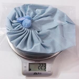 Gros plan d'un bonnet bébé bleu clair avec oreilles de lapin pesant 22,3g