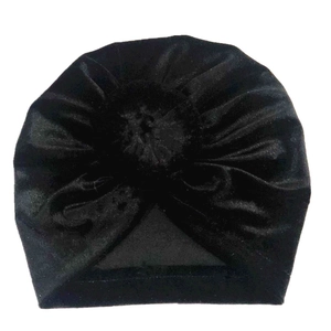Detail of soft black velvet baby turban hat with a pleated donut flower decoration